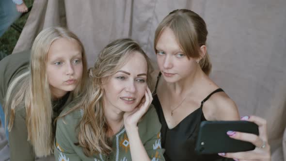 Close Up of Smiling Mother with Daughters Makes Funny Selfies on the Smartphone Grimacing alt