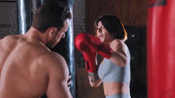 Boxing Training in the Gym  Woman Boxer Training Her Punches on Punching Bag with Trainer alt