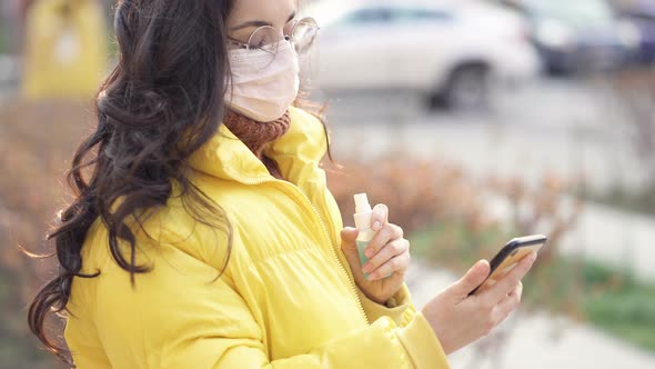  Woman using sanitizer spray on the mobile phone.