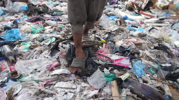 Poverty Boy's Legs Walking On Garbage Dump alt