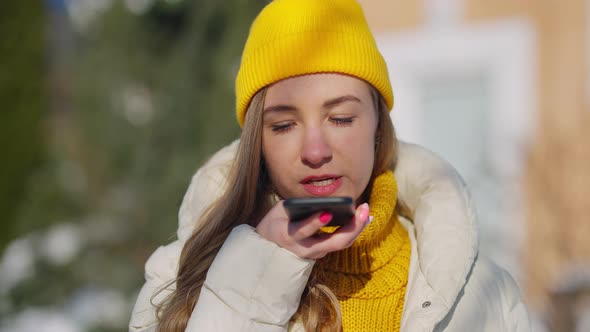 Closeup Portrait of Confident Female Millennial Recording Voice Mail on Smartphone Outdoors alt