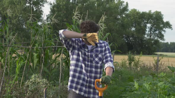 Young worker was tired. Holding a shovel in the garden. gloved hands