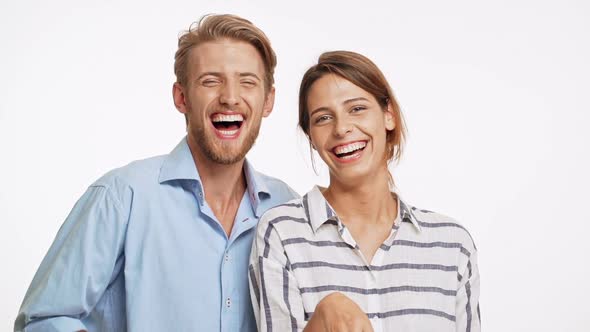Funny Caucasian Couple Looking at Camera and Laughing in Slowmotion on White Background alt