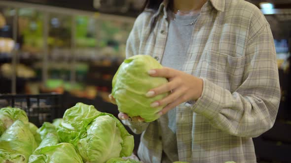 Woman in Supermarket Choosing Young Cabbage