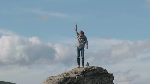 Funny Man Jumping on Top Cliff Celebrates Climbing to Mountain on Sunny Day alt