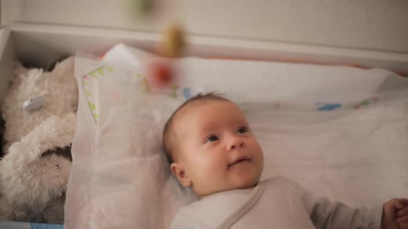 Portrait of happy little baby girl laying on changing table alt