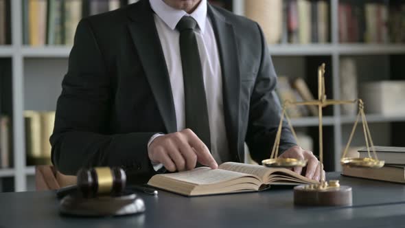 Close Up Shoot of Lawyer Hand Reading Book on Court Room Table alt