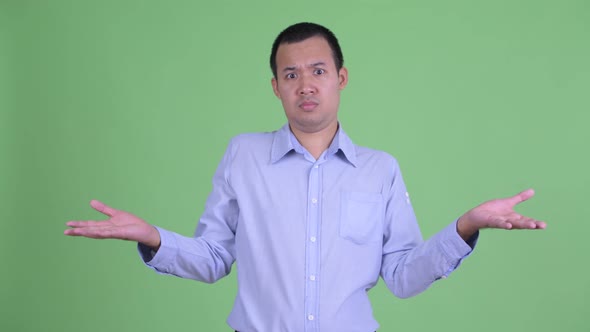 Confused Asian Businessman Shrugging Shoulders alt