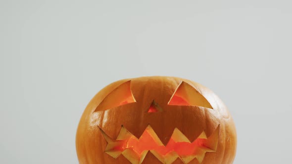 Close up view of scary face carved halloween pumpkin against grey background alt