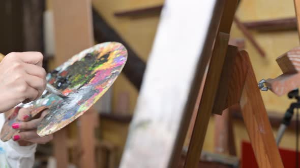 Creative Female Painter Mixes Palette of Oil Paints in Palette alt