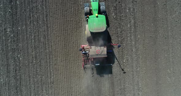 Aerial footage of farmer with tractor with seeder, sowing (seeding) crops at agricultural field. alt