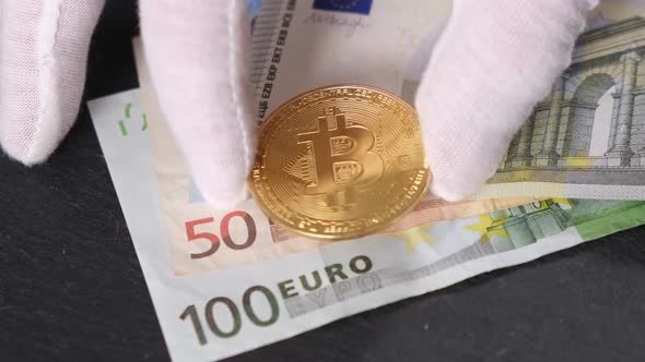 A Man's Hand Puts Bitcoin Coins On Euro Bills