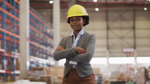 Portrait of african american female worker wearing helmet and smiling in warehouse alt