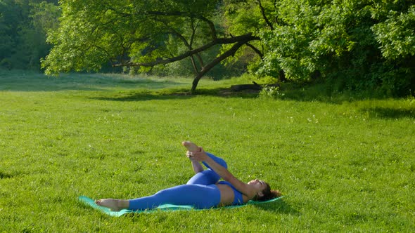 Young Beautiful Girl Doing Fitness Workout on the Grass in the Park alt