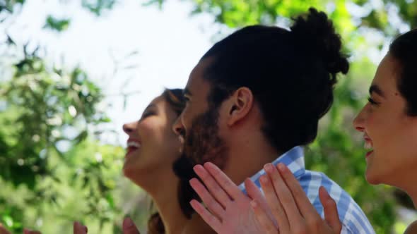 Friends at outdoor lunch applauding for woman alt