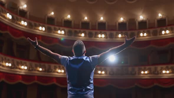 Man performing with gestures on stage.  alt