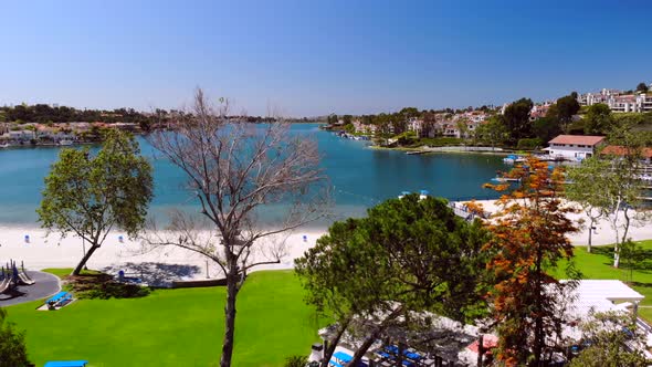 Aerial drone rising through trees and flowers over community Lake Mission Viejo alt