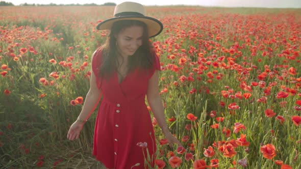 Beautiful Girl Walks in a Field Among Poppies