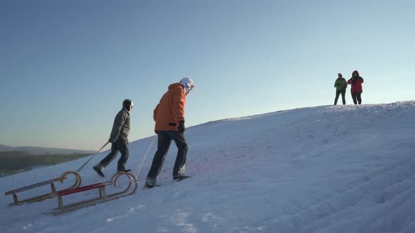 Active Senior Couples Enjoying Winter Day Outdoors With Sled and Tea alt