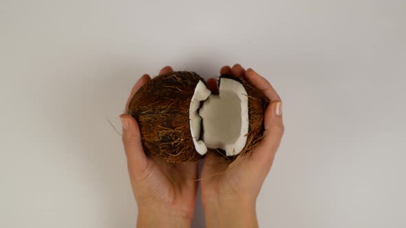 Beautiful female hands open and close a broken coconut in studio lighting
