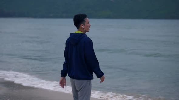 Handsome man running on the beach looking out at sea view.