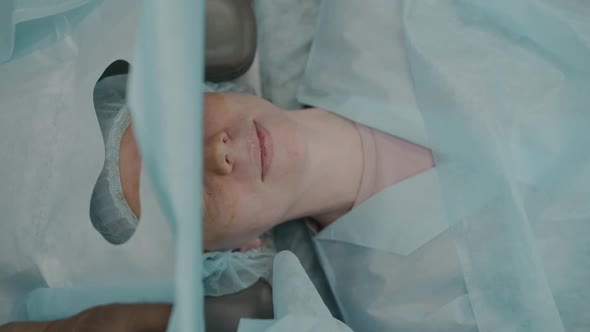 Woman Is Prepared for Blepharoplasty, Nurse's Hands Put Sheet on Patient's Face alt