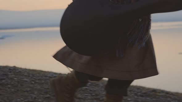 Man In Boots Carrying Guitar Case At Sunset alt