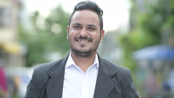 Face of Happy Bearded Indian Businessman Smiling Outdoors alt