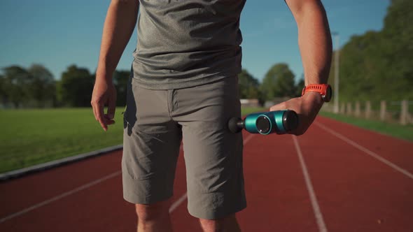 An Athlete Massages with a Percussion Therapy Gun to Relieve the Pain of Muscle Aches After a alt