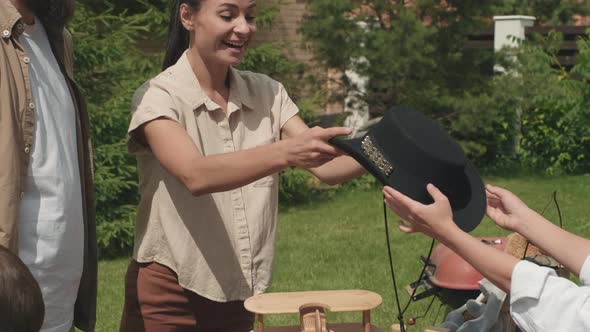 Happy Neighbor Trying on Hat at Garage Sale alt
