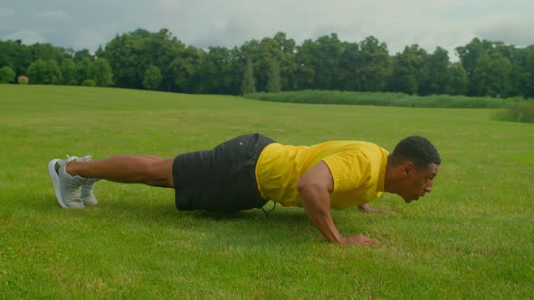 Motivated Sporty Fit African Man Doing Advanced Push Up Exercise in Nature alt