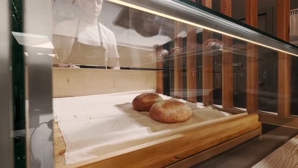 Baker Throws Out From the Baking Sheet Freshly Baked Golden Croissants on Showcase in Coffee Shop alt