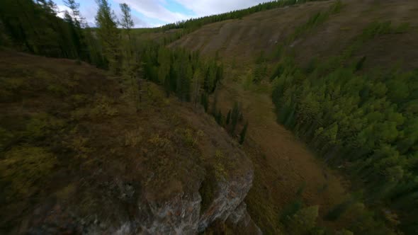 FPV Sport Drone Cinematic Shot Flying Over Spruce Forest and Cliff alt