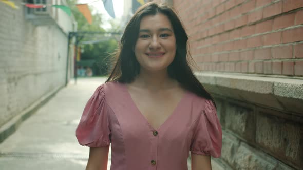 Portrait of Attractive Asian Woman Student Showing Thumbsup Hand Gesture and Smiling Outdoors alt