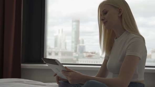 Young Attractive Woman Makes Video Calls in the Bedroom with a Large Window alt