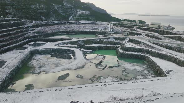 Drone shot of Quarry. Snow covered mine. Open sky pit. Rock mining business. Sea alt