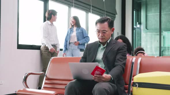 Asian businessman uses laptop computer for working, waiting for flight at terminal at airport