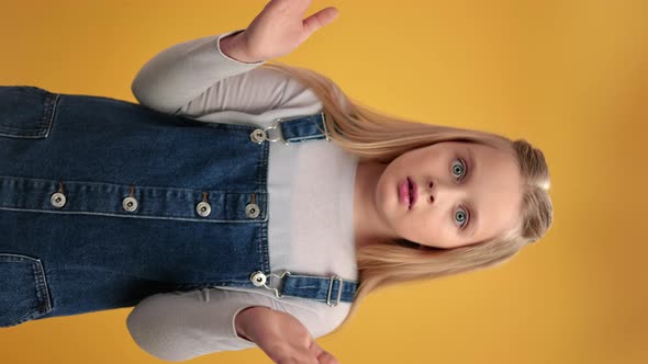 VERTICAL VIDEO POV Portrait Amazement Girl Gesturing Dont Know Not Sure Posing Isolated on Orange alt