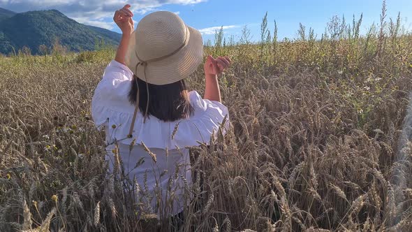 a brunette woman is sitting in a wheat field view from the back 