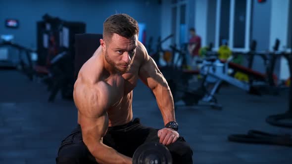 Handsome power athletic man bodybuilder doing exercises with dumbbell. alt