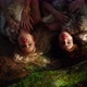 Two Women in Clothes Made of Natural Fur Lie on Grass in Forest and Sing a Song - VideoHive Item for Sale