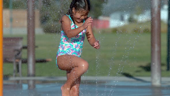 Girl playing in sprinkler at park in super slow motion