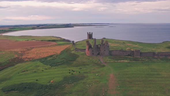Dunstanburgh Castle at sunset, a famous landmark in Northumberland, England, UK. Aerial drone view alt