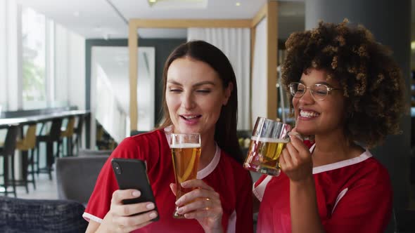 Diverse group of happy friends watching a game drinking beers and taking a selfie at a bar alt