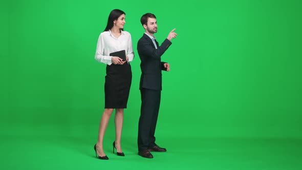Couple of Young People in Suits Man and Woman Stand in the Green Space of the Chromakey Watching and alt