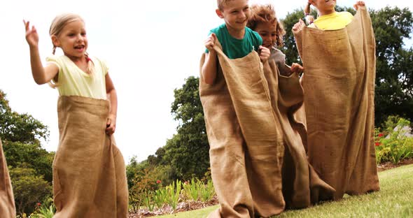 Kids having a sack race in park alt