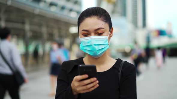 business woman using smartphone and wearing medical mask for protection from coronavirus alt