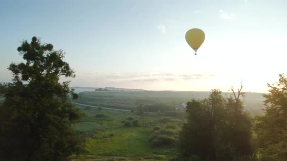 Colorful Hot Air Balloons Fly Over Green Meadows and Morning Fog at Sunrise. Travel, Adventure alt