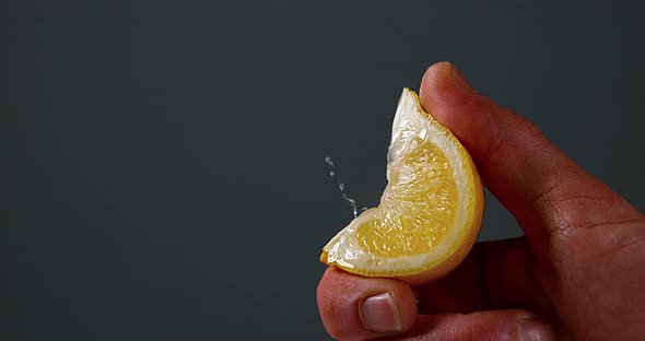 Hand of Man Squeezing Lemon, citrus limonum against Black Background, Slow Motion 4K alt