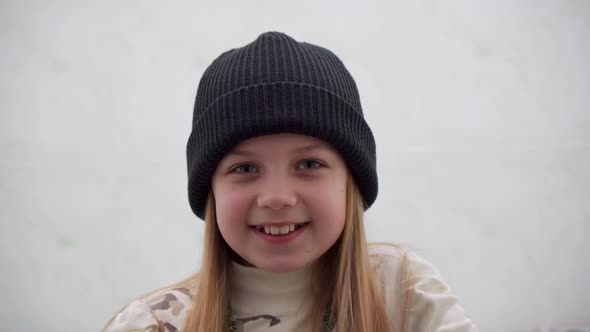 Cheerful Positive Girl of School Age in a Warm Hat on a White Background